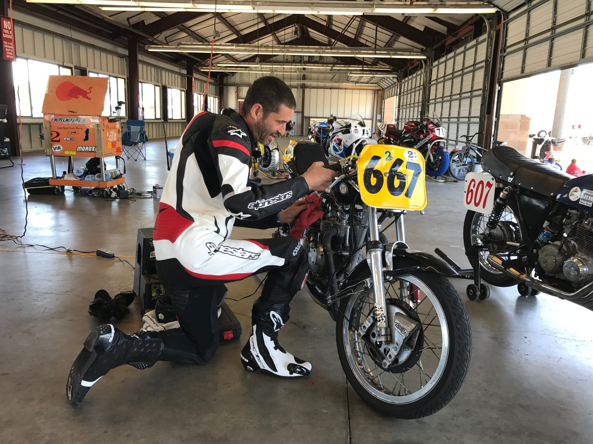 An image of Larry from New York City Motorcycles performing a last minute tune-up on his bike wearing full race leathers.