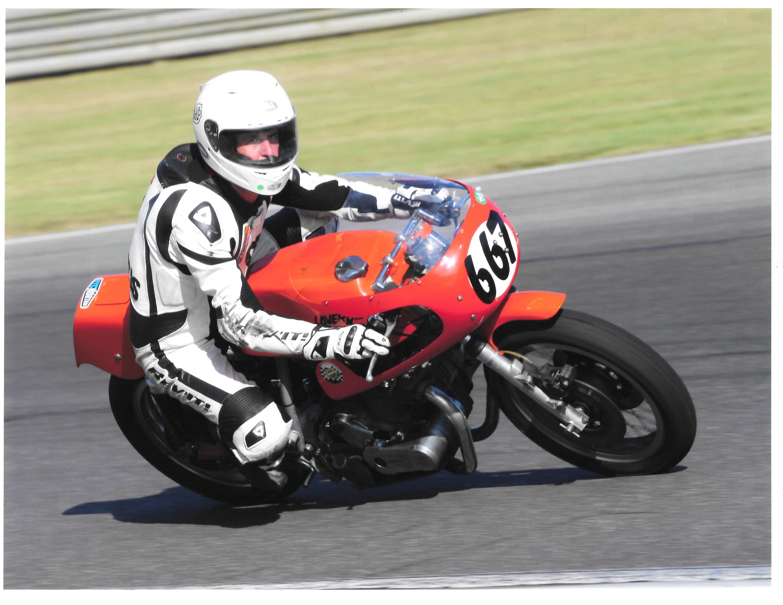 An image of Larry from New York City Motorcycles racing an orange, vintage Laverda motorcycle on a track.