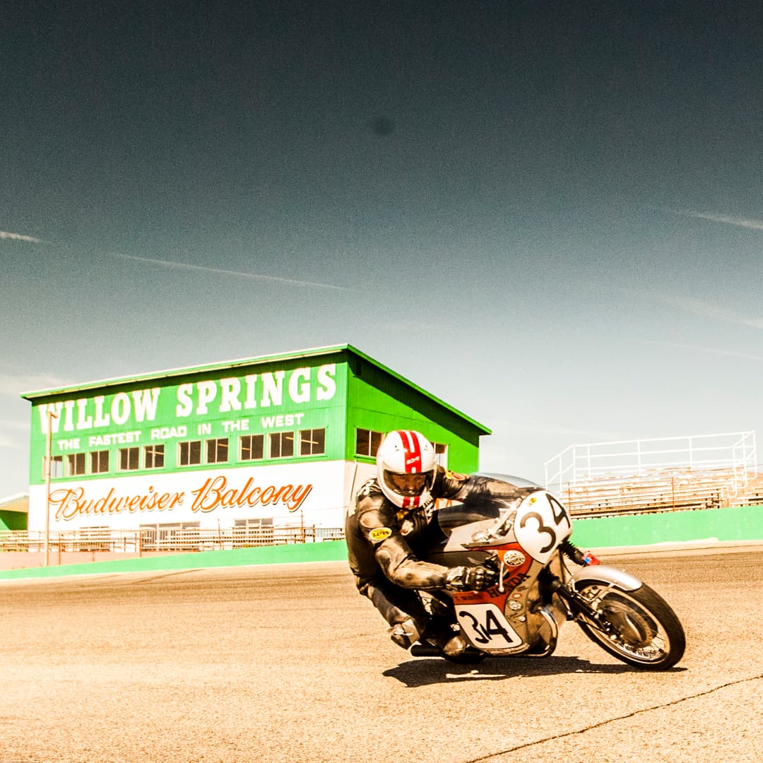 An image of Larry from New York City Motorcycles racing a vintage Honda motorbike. He's riding at Willow Springs - the fastest road in the west.