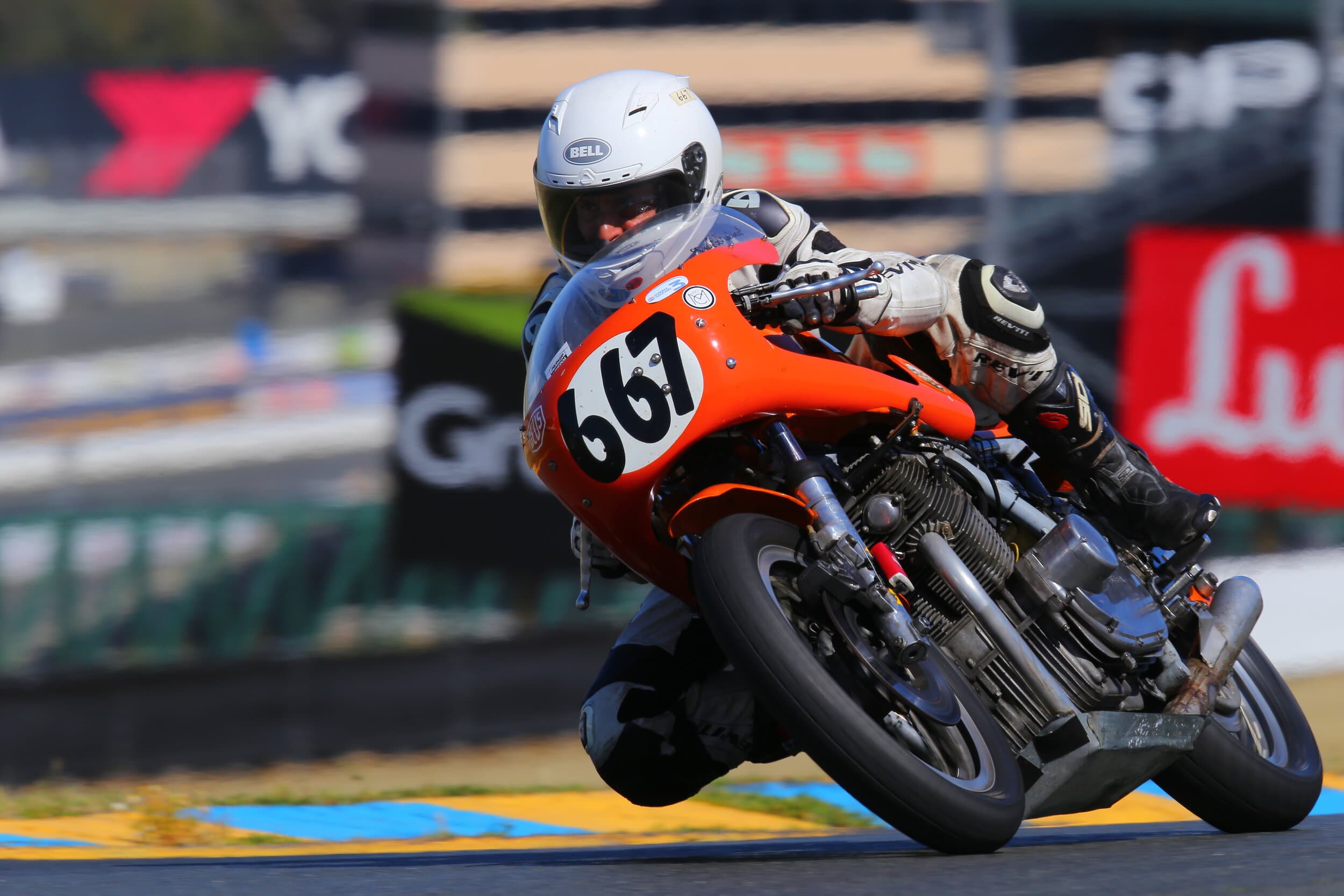 An image of Larry from New York City Motorcycles racing a vintage orange Laverda around a track.